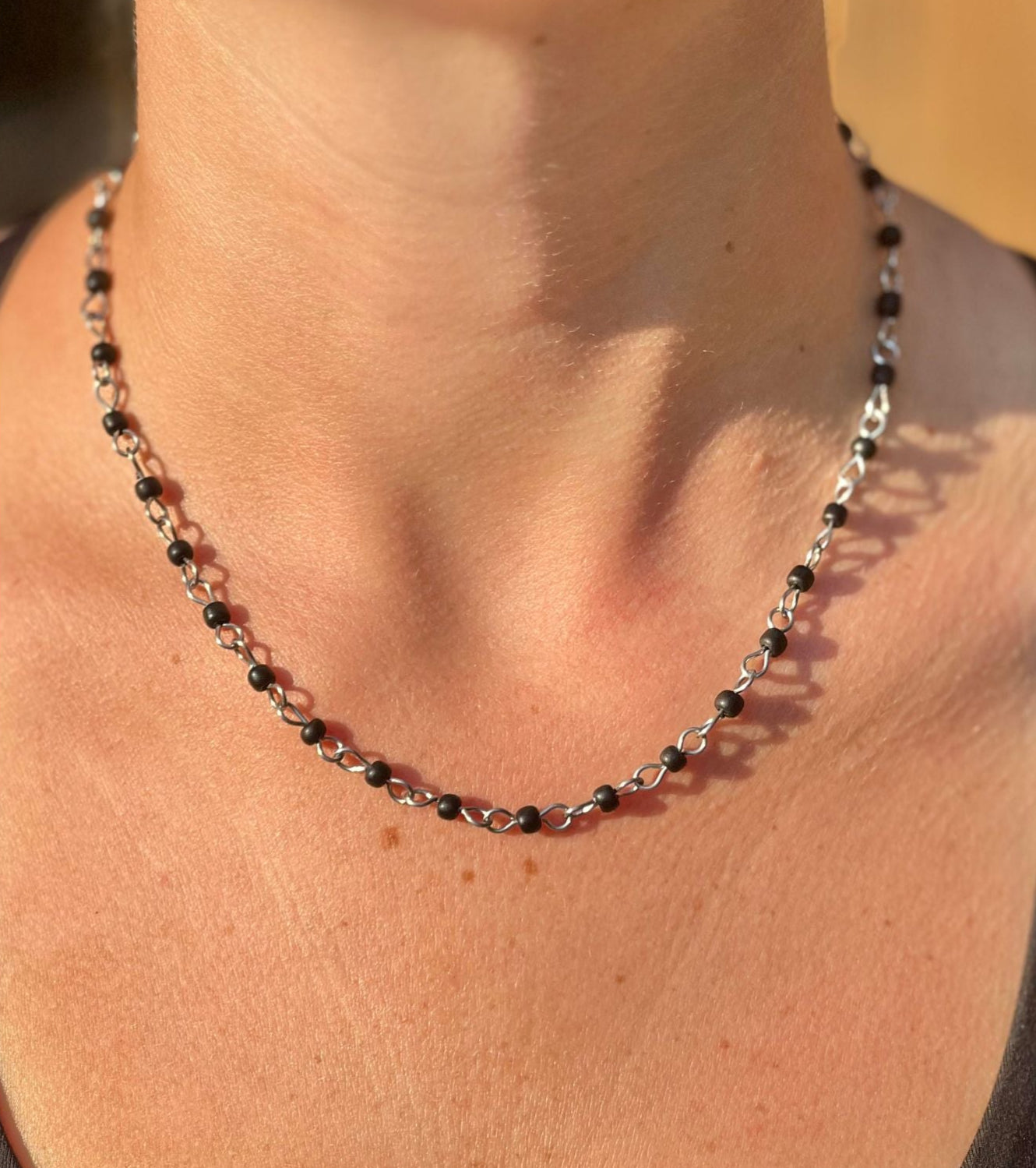 Necklace with black and silver beads worn by a person