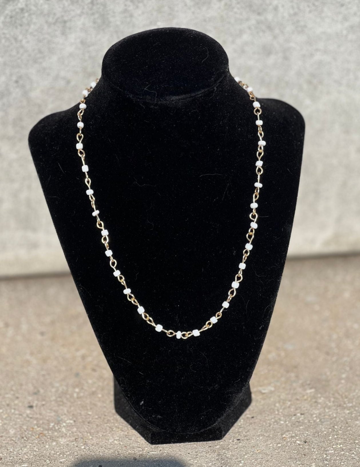 Necklace on a black velvet bust against a gray background