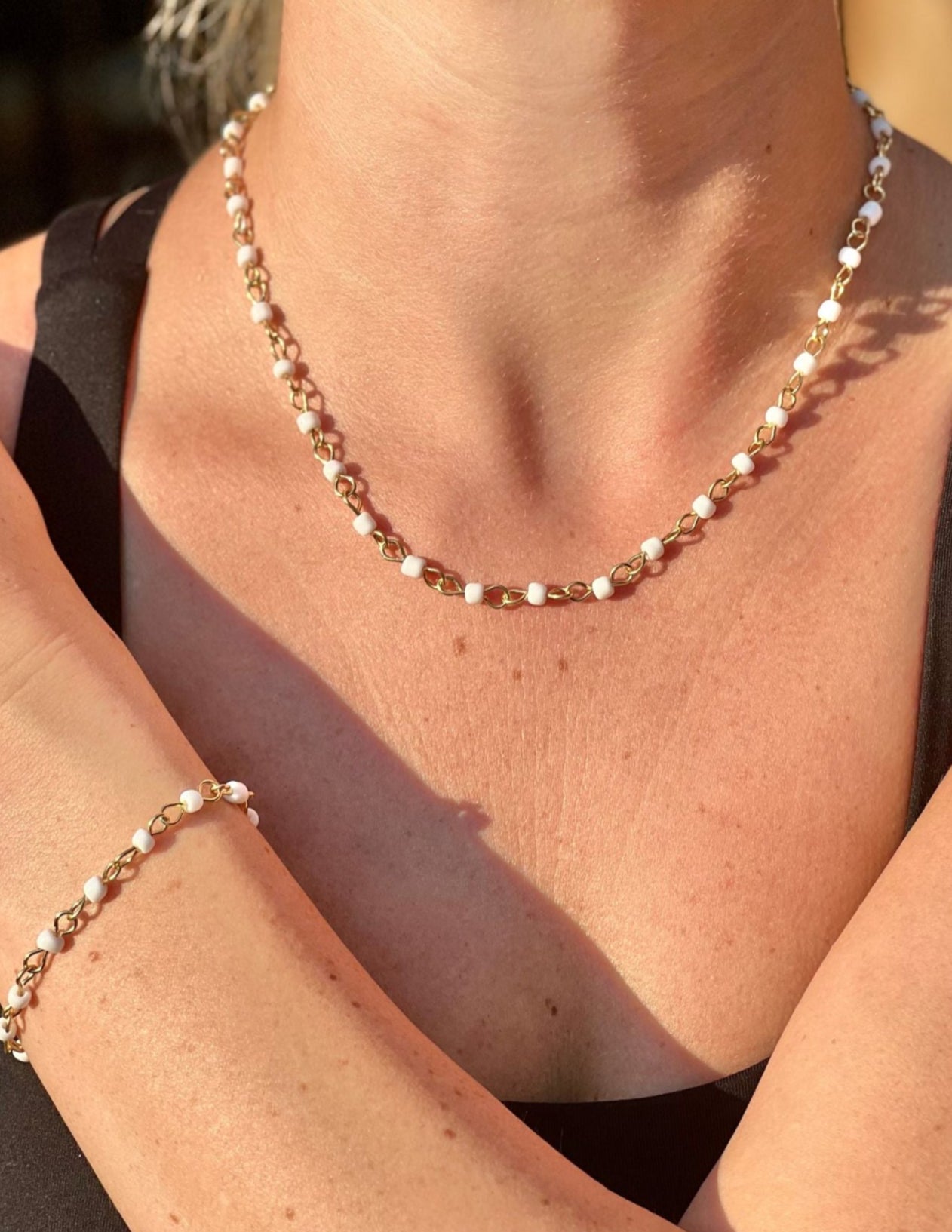 Necklace and bracelet on a person's arm with a blurred background