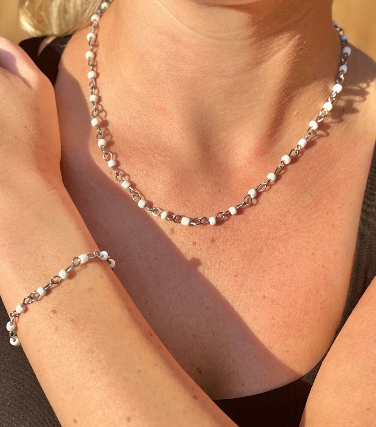 Person wearing a silver necklace and bracelet with a blurred background
